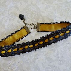 "Harvest gold grosgrain ribbon with a black lace stitched overlay make up this choker style necklace. The lace and ribbon are crimped with antique brass crimp bars and there is an extension matching chain for adjustable fit.  Choker closes at 13\" on first link and with extension chain will adjust to 15\". The chain is accented with a black bead dangle and there is a hook closure on the choker." Halloween Choker, Black Lace Choker Necklace, Black Lace Choker, Lace Choker Necklace, Ribbon Choker, Harvest Gold, Lace Choker, Choker Style Necklace, Orange Ribbon