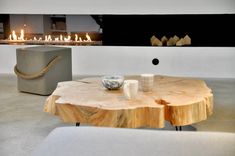 a wooden table sitting next to a fire place on top of a white floor in front of a fireplace