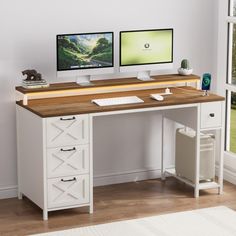 two computer monitors sitting on top of a wooden desk