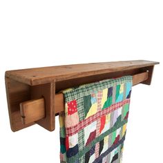 a wooden towel rack with a patchwork quilt hanging from it's back end