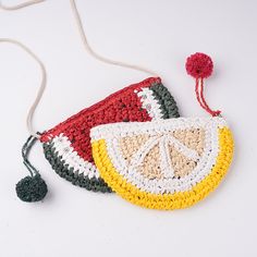 two crocheted purses sitting next to each other on a white surface with a red pom - pom