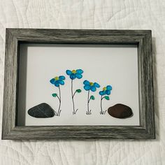 some rocks and flowers in a frame on a bed