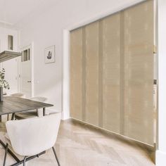 a dining room table with white chairs next to a window covered in sheer shades and blinds