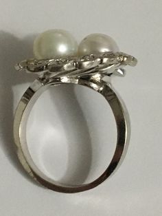 Details: A Unique and one of a kind Ring Handmade Vintage Ring Custom Made Ring (Estimated Late 1960's Early 1970's) 14Karat White Gold Ring Shank is nice and wide 2 Cultured Pearls in the Center One Pearl color is White the other has a silver tone color There are 12 diamond Stones around the Crown Estimate Total Weight .25ct Ring weight : 7.3 Grams Ring is appraised for the value of $2750 Since the following ring is Vintage no changes will be made to the ring Ring will be shipped via FEDEX seco Oval Diamond Pearl Ring For Formal Occasions, Platinum Multi-stone Cluster Ring, Vintage Platinum Ring With Gemstone, Fine Jewelry Round Cut Pearl Ring For Anniversary, Diamond White Oval Pearl Ring For Anniversary, Formal White Gold Fine Jewelry Ring, Fine Jewelry White Gold Pearl Ring With Prong Setting, Collectible Round White Gold Diamond Ring, White Gold Pearl Ring With Prong Setting