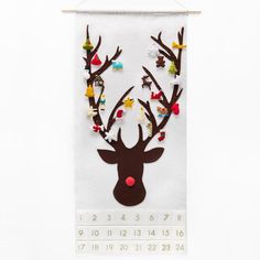 a white wall hanging with a reindeer head on it's side and colorful beads around the antlers