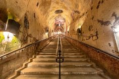 a long set of stairs leading up to the ceiling in a tunnel with lights on either side