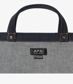 A.P.C. tote bag.  - Unisex model. - Two large handles. May be carried by hand or on shoulder. - Exterior pocket embroidered with caramel-colored A.P.C. logo. - Interior pocket. - Rivets engraved A.P.C. - Caramel-colored topstitching. Designer Everyday Bag Medium Size, Designer Medium Bags For Everyday Use, Designer Everyday Medium Bag, Designer Medium Everyday Bag, Large Satchel With Dust Bag For Errands, Designer Canvas Tote Bag With Top Carry Handle, Designer Canvas Tote Bag With Top Handle, Large Satchel With Dust Bag For Daily Use, Top Handle Canvas Bag For Errands