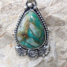 An unusual Chrysocolla teardrop-shaped stone features crystal-like matrics within the stone. The teardrop shape stone is framed with a beaded wire. At the bottom of the pendant, there are handmade Moroccan-style flower and leaf motifs giving this pendant a Moroccan flare. The cool blues and greens of this stone will pair nicely with most of your wardrobe. Unique Agate Teardrop Pendant Jewelry, Unique Teardrop Pendant Agate Jewelry, Nature-inspired Teardrop Pendant Jewelry For Healing, Teardrop Agate Necklace With Large Stone, Turquoise Drop Bohemian Jewelry, Turquoise Bohemian Drop Jewelry, Bohemian Turquoise Drop Jewelry, Turquoise Agate Teardrop Jewelry, Turquoise Teardrop Agate Jewelry