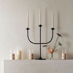 a black candelabra with candles and flowers on the mantle next to it