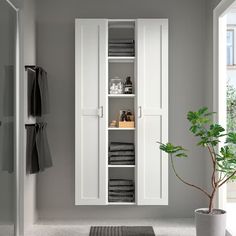 a bathroom with a white cabinet next to a potted plant