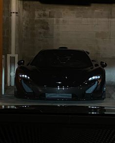 a black sports car is parked in a garage with its hood up and lights on