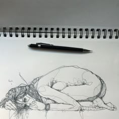 a pencil drawing of a person sleeping on their stomach with a pen next to it