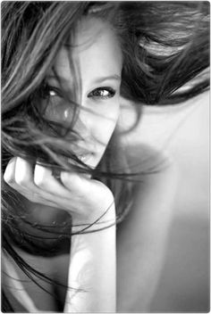 a black and white photo of a woman with her hair blowing in the wind