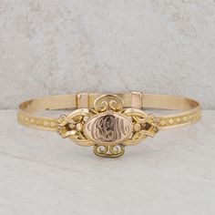 This children's gold plated bangle features an oval shaped monogram at its center, accented by filigree detailing, along with a diamond pattern around the rest of the bracelet. At the center, the initials "CLM" are engraved. This bracelet design is an adjustable to put on the wrist but it can only be worn at 5" inches. The bangle weighs 10.20 grams and measures in height 19.5mm. It can also be on a smaller ladies wrist but due to the size, it would more than likely be for a smaller child. Condit Classic Bracelets With Decorative Band As Gift, Classic Adjustable Cuff Bracelet With Intricate Design, Formal Cuff Bracelet With Intricate Design, Yellow Gold Oval Jewelry With Decorative Band, Elegant Oval Hallmarked Bangle, Oval Yellow Gold Jewelry With Decorative Band, Heirloom Cuff Bracelet With Intricate Design For Formal Occasions, Decorative Oval Yellow Gold Jewelry, Classic Gold Bracelet With Intricate Design For Anniversary