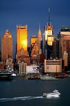 the city skyline is lit up at night, with boats on the water in front of it