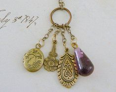 "Vintage Jewelry - Vintage Necklace - Charm Tassel Necklace - Locket Necklace - Amethyst Necklace - Chloes Vintage Jewelry- handmade jewelry This is such a sweet vintage necklace. Vintage brass chain embellished with purple glass beads and small brass charms and a tiny locket. Such an exquisite delicate necklace. Chloe says, \"Wear it and feel fabulous!\" The charms measure 1 3/4\" long from the top of the ring. You can choose the necklace length you would like at checkout. Thanks for visiting C Handmade Spiritual Dangle Charm Necklaces, Bohemian Handmade Dangle Charm Necklaces, Bohemian Handmade Dangle Charm Necklace, Artistic Nickel-free Purple Jewelry, Artistic Purple Nickel-free Jewelry, Bohemian Bronze Necklaces With Charms, Bronze Bohemian Necklace With Charms, Bohemian Bronze Necklace With Charms, Unique Purple Dangle Necklaces