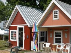 a small red house with a white porch and umbrellas on the front patio area