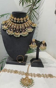 an elaborate necklace and earring set is displayed on a table next to a potted plant