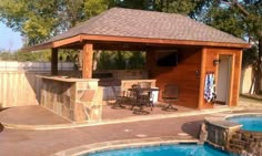 a backyard with a pool, grill and covered patio area next to a swimming pool