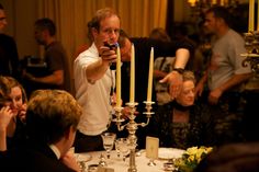 a man holding a cell phone while standing in front of a table filled with people