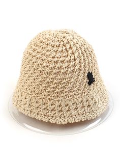 a crocheted hat with a black flower on the front and bottom, sitting on a clear plate