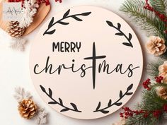 a merry christmas sign surrounded by pine cones and other holiday decorations on a white surface