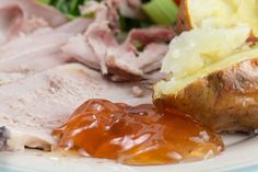 a white plate topped with meat, potatoes and gravy next to a salad