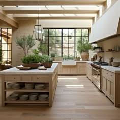 a kitchen with wooden floors and lots of counter space next to a window that has potted plants on it