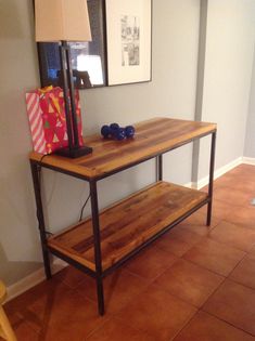 a wooden table with a lamp on top of it next to a painting and other items