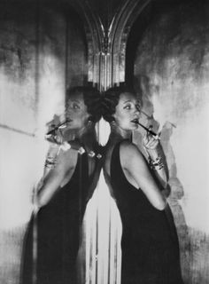 black and white photograph of two women in front of a mirror brushing their teeth with toothbrushes