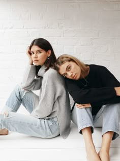 two women sitting on the floor with their arms around each other