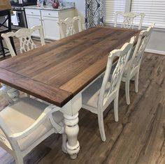 a kitchen table with chairs around it in a room that has hardwood floors and white cabinets