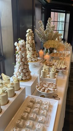 a table with many different types of desserts on it and candles in the background