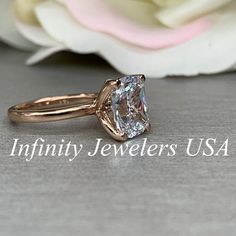 a close up of a diamond ring with flowers in the background