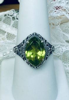 Natural Green Peridot Ring Iris Design#201 Custom Made This is a stunning Art Deco vintage reproduction ring in sterling silver filigree with a 3.12 carat Natural green peridot gemstone. The brilliant natural gem is 13mm in long by 9mm wide. The ring is 17mm North-South on the finger. The inside of the band is marked 925 for solid sterling silver. This is a lovely reproduction of a vintage antique filigree ring. There is beautiful craftsmanship evidenced in the silver filigree setting. See the f Classic Green Gemstones With Accents, Classic Peridot Jewelry With Accent Stones, Green Marquise Jewelry With Accent Stones, Classic Green Gemstone With Center Stone, Green Marquise Rings With Accent Stones, Green Marquise Sterling Silver Jewelry, Green Gemstone Ring With Marquise Cut, Green Marquise Cut Gemstone Jewelry, Green Marquise Cut Gemstone Ring