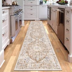 a large rug in the middle of a kitchen with white cabinets and stainless steel appliances