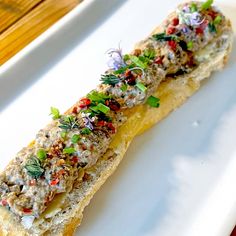 a piece of bread with various toppings on it sitting on a white platter