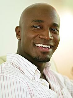 a man is smiling for the camera in front of a wall with photos on it