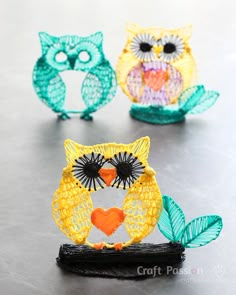 three colorful owl figurines sitting on top of a table