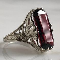 Details: Stunning Edwardian Period garnet and 14K white gold filigree ring! The stone measures 14.5mm by 7mm, and the is 4.6mm above the finger at the highest point on the ring. The filigree is beautiful on this ring, and is in lovely shape. This is a stunning ring--you will not be disappointed! Please ask all necessary questions prior to placing an order. Measurements: The size is 4 1/2 US and can be sized for a fee. Condition: The overall all condition of this ring is very good. Vintage Ruby Ring With Filigree For Wedding, Ornate 14k Gold Ruby Ring For Anniversary, Antique Ruby Filigree Wedding Ring, Red Hallmarked Engraved Ring For Formal Occasions, 14k Gold Filigree Ruby Ring Gift, Elegant 14k Gold Ruby Ring With Intricate Design, White Gold Engraved Ring With Gemstone For Formal Occasions, 14k Gold Ruby Ring With Filigree For Gift, Ruby Ring With Intricate Design For Wedding