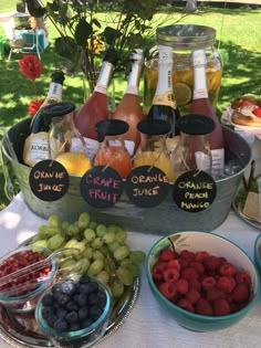 an assortment of fruits and drinks on a table with labels that say grape juice, orange juice, cranberry juice, lemonade punch