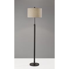 the floor lamp is black and has a beige fabric shade on it, with an iron base