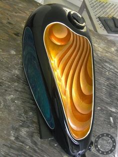 a black and gold vase sitting on top of a wooden table