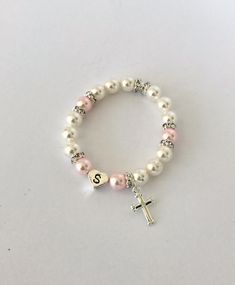 "Gift someone special this timeless gift of a classic pearl bracelet. Swarovski 6mm pearls in white and rosaline circle the wrist and frame a sterling silver heart initial bead. Sparkly rhinestone rondelles add a touch of glitz, and a sterling silver cross hangs by the initial. The bracelet is created on elastic cord for easy on/off. - - - -> WHAT SIZE SHOULD YOU BUY? The listing photo shows a 6 1/2\" bracelet. It's always best to measure a bracelet that currently fits the recipient, but if y Classic Personalized White Pearl Bracelet, Classic White Pearl Bracelet For Mother's Day, Classic Pearl Stretch Bracelet Gift, Classic Pearl Stretch Bracelet For Gifts, Classic Pearl Stretch Bracelet As Gift, Elegant Adjustable Rosary Bracelet For Birthday, Classic White Bracelets For Mother's Day, Classic Personalized Pearl Bracelet, Personalized Classic Pearl Bracelet