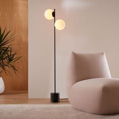 a living room with a chair, lamp and potted plant on the floor next to it