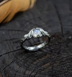 a close up of a ring on a piece of wood with a feather in the background