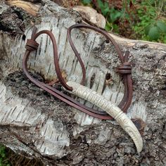 an animal's tooth is on a leather cord attached to a piece of wood