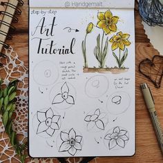 an open notebook with some flowers on top of it next to pens and paper clips