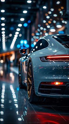 the back end of a white sports car in a parking garage with lights on at night