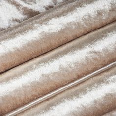 a close up shot of the fabric on top of a bed with white and brown colors